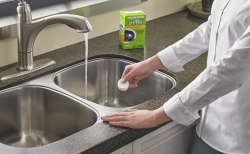 A person holding an affresh® disposal cleaner tablet 