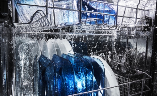 A load of dishes being washed on the racks of a dishwasher 