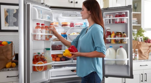 Woman loading drinks in the refrigerator door