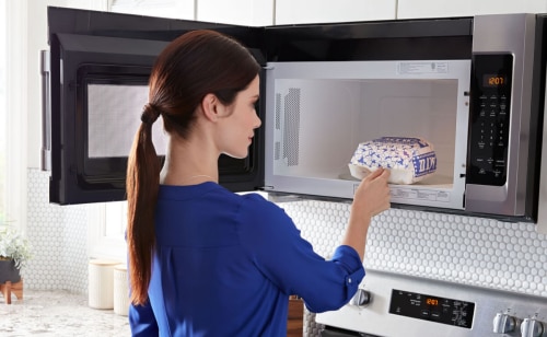 Person standing in front of an open over-the-range microwave