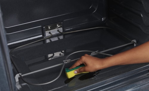 A person scrubbing the inside of an oven