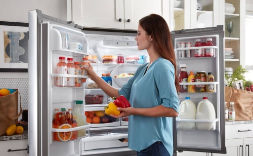 Person loading juice drinks into the door of a French door refrigerator