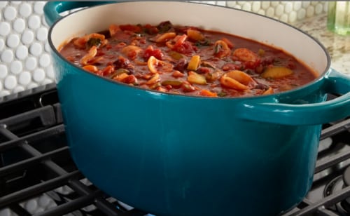 A dish of food simmering on a gas stovetop