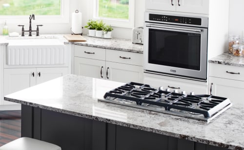 Open kitchen with gas stovetop on center granite countertop island