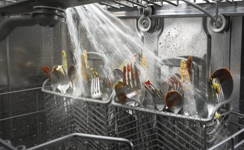 Dishes being sprayed with water on the inside of a dishwasher
