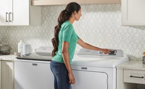 User pressing button on white front load dryer