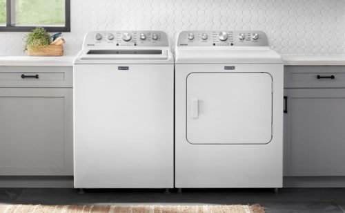 White front load laundry pair in between grey cabinets in a laundry room