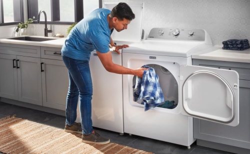 Man putting plaid shirt in Maytag® dryer.