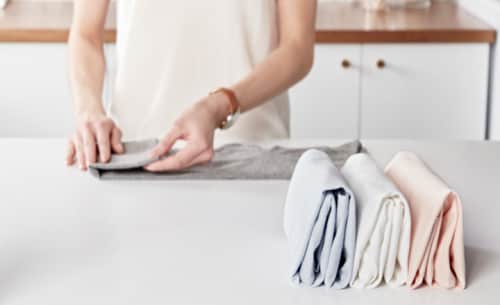 A person folding laundry and lining it up neatly 