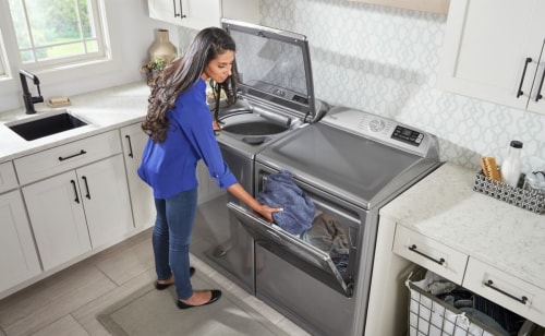 A person switching clothes between a washer and a dryer