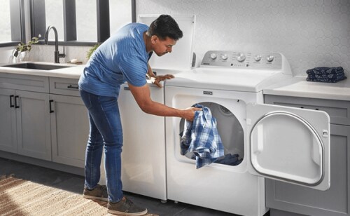 A man puts a shirt in a white Maytag® dryer