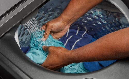 erson washing a garment in their washer’s  built-in sink