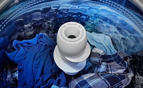 Agitator surrounded by blue clothes in Maytag® top load washer