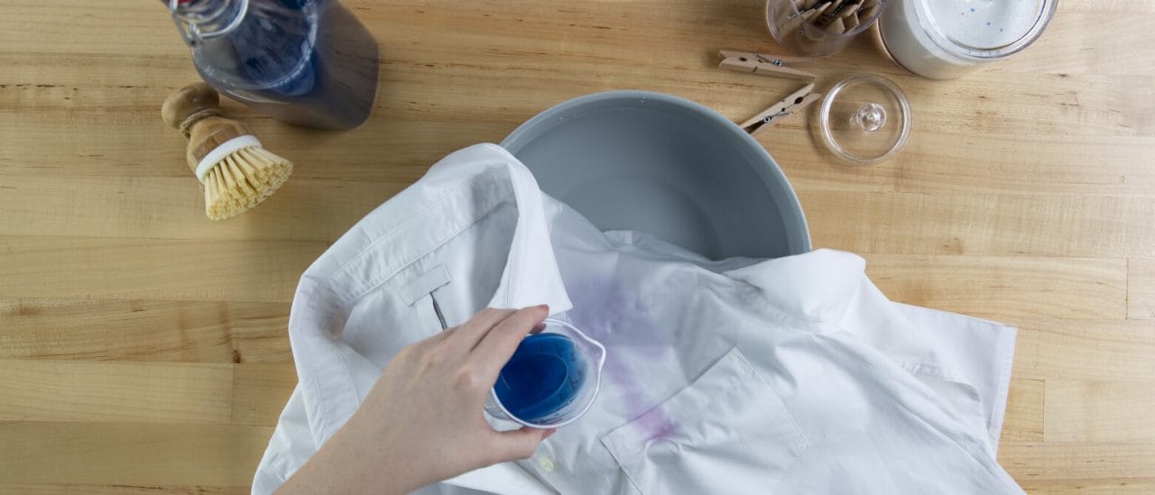 Someone showing how to remove a red wine stain from a white shirt