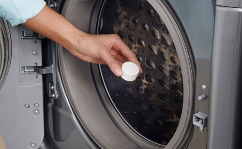 Person using affresh® tablet in washing machine