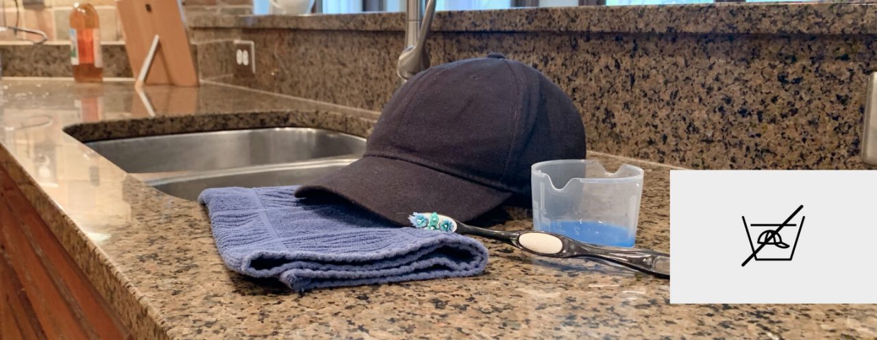 A baseball cap and cleaning supplies on a kitchen counter