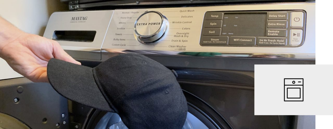 A person placing a baseball cap into a Maytag® washer