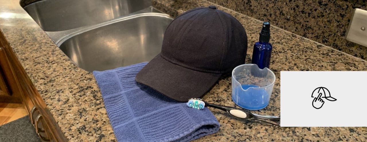 A baseball cap, cleaning supplies and a toothbrush next to a sink