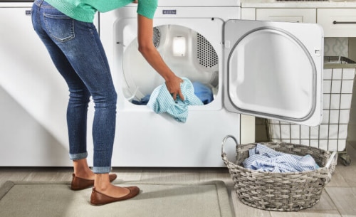 Woman loading blue shirt into a Maytag® dryer