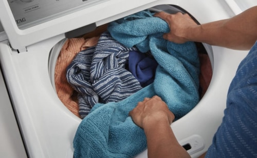 Person adding laundry to a washing machine