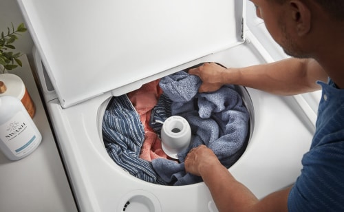 A person putting laundry in their washing machine