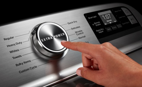 A person adjusting controls on a stainless steel dryer