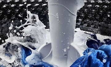 Inside of a top load washer showing agitator and water splashing.