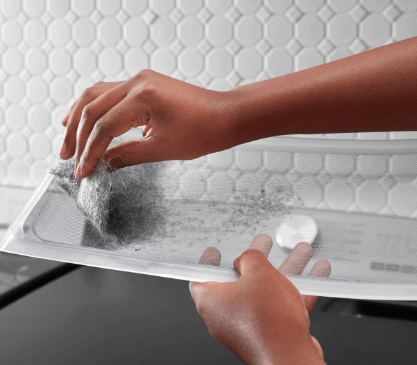 A person pulling lint off the XL lint trap