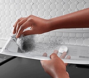 A person pulling lint off the XL lint trap