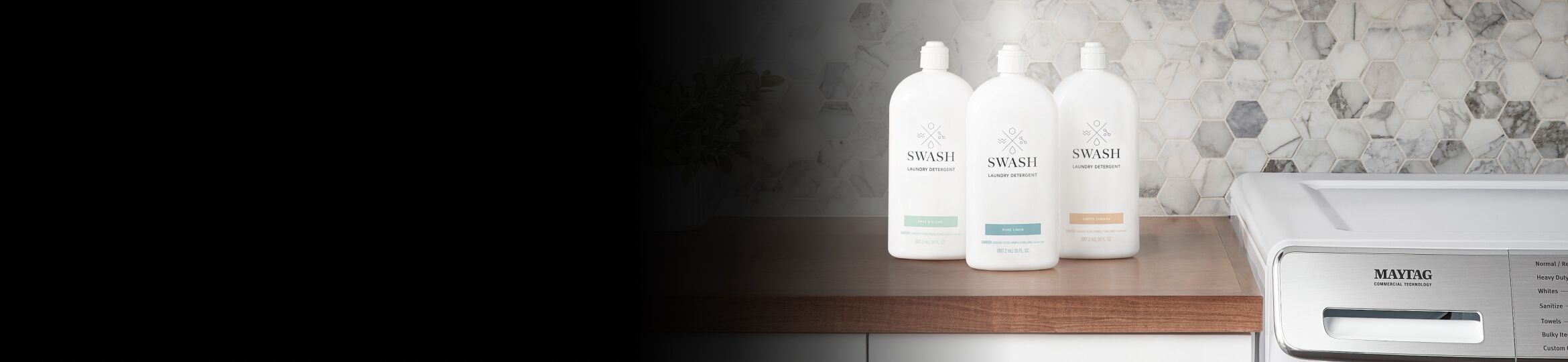 Three bottles of Swash® laundry detergent on a counter next to a Maytag® washing machine.