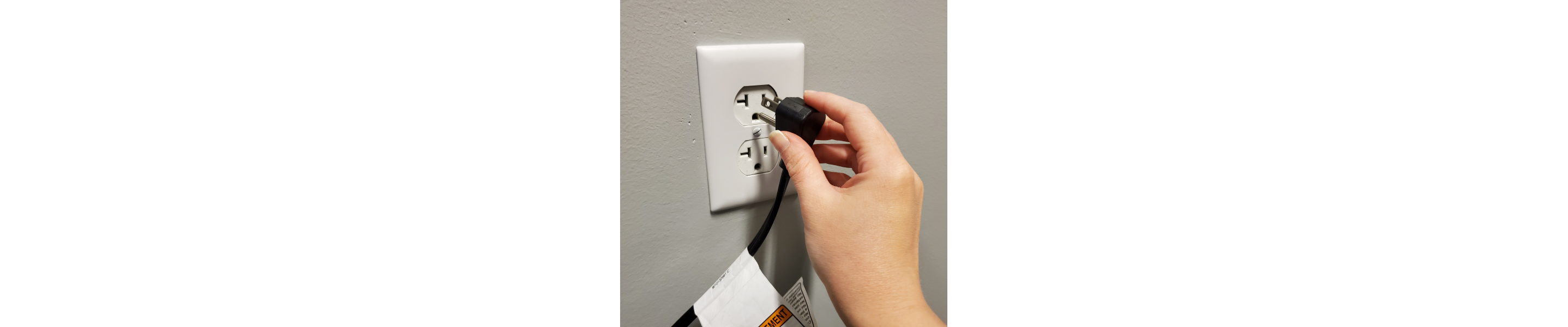 A hand unplugging a refrigerator cord from an outlet.