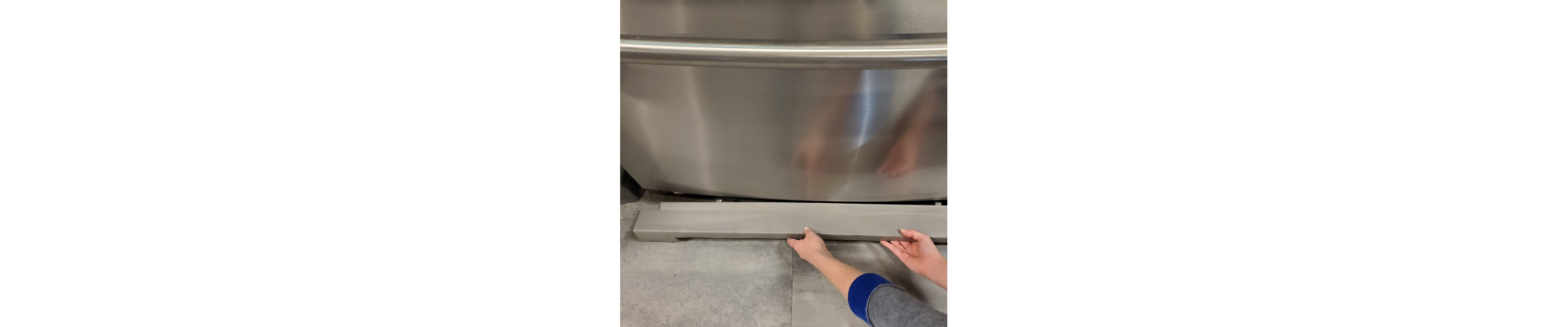 Hands removing the base grille on a refrigerator.