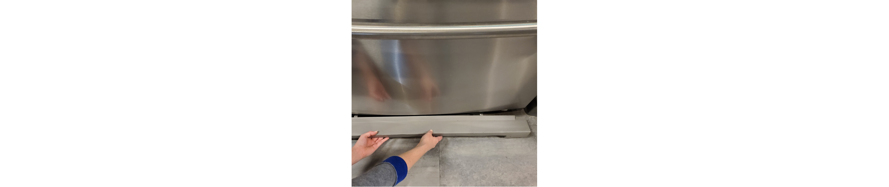 Hands replacing the base grille on a refrigerator.