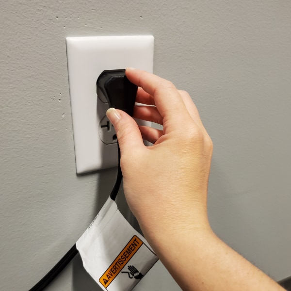 A hand plugging a refrigerator cord into an outlet.