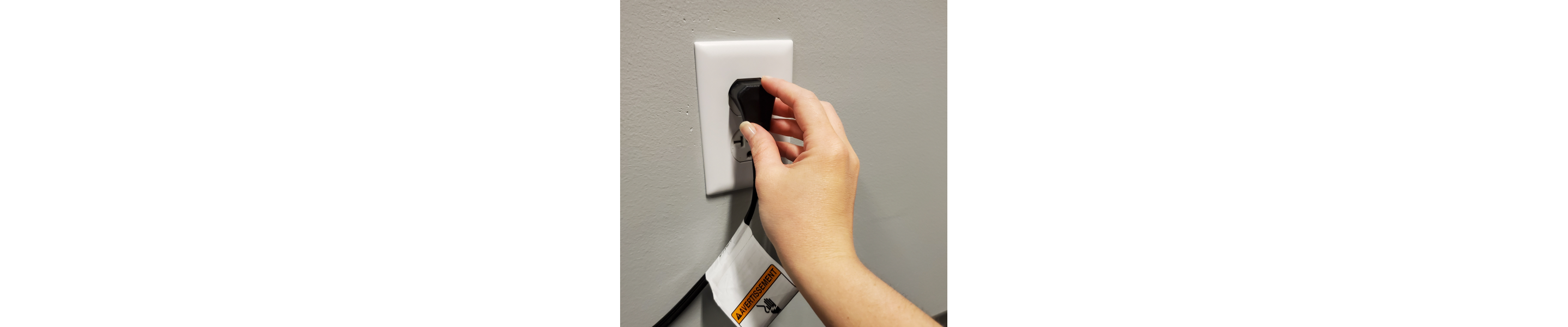 A hand plugging a refrigerator cord into an outlet.