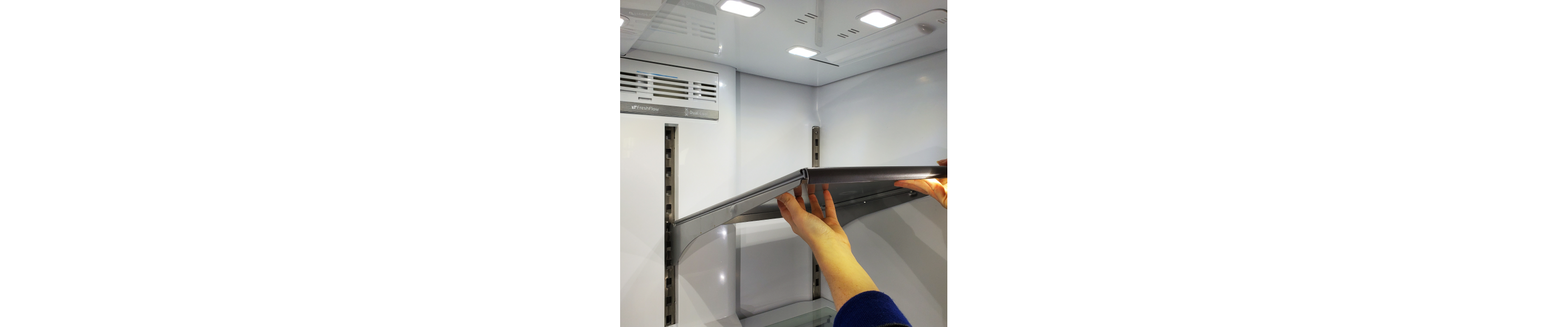 Hands lifting a shelf out of a fridge.