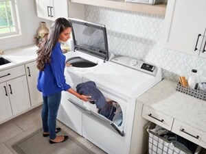 Person transferring clothes from a top load washer to the dryer