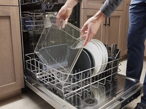 Person loading dishes into bottom rack of open dishwasher
