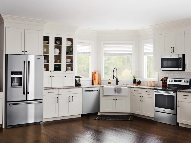 Stainless steel Maytag® appliance suite in open kitchen with white cabinetry