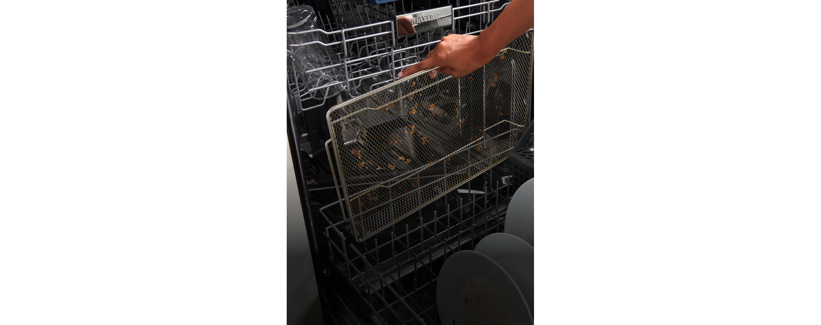 A used air fry basket getting placed into the dishwasher.