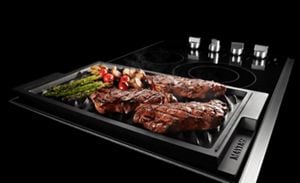 Grill side of cooktop with steak and asparagus on it.