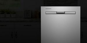 A stainless steel dishwasher against a dark background.