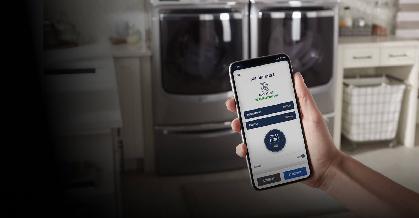 Image of a smartphone displaying the Maytag® app with a washer and dryer in the background.