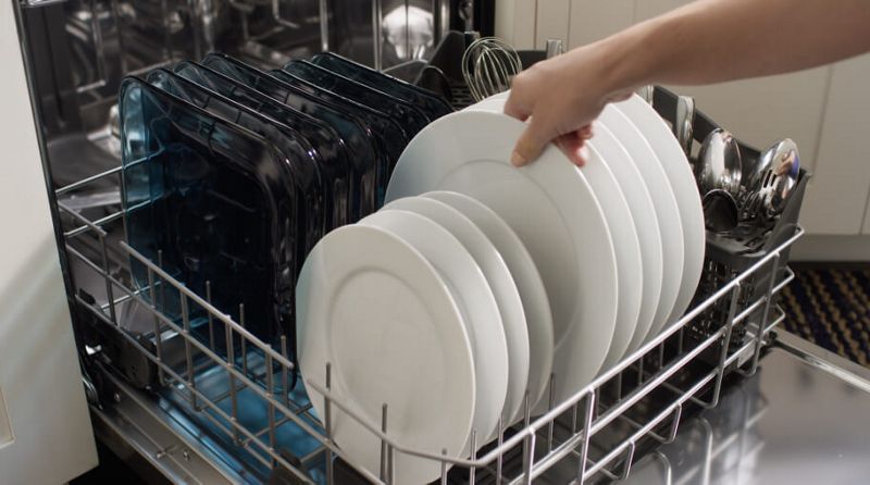 Hand unloading clean dishes from the dishwasher