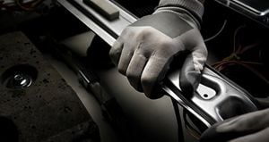 Hand with work glove assembling a laundry machine.