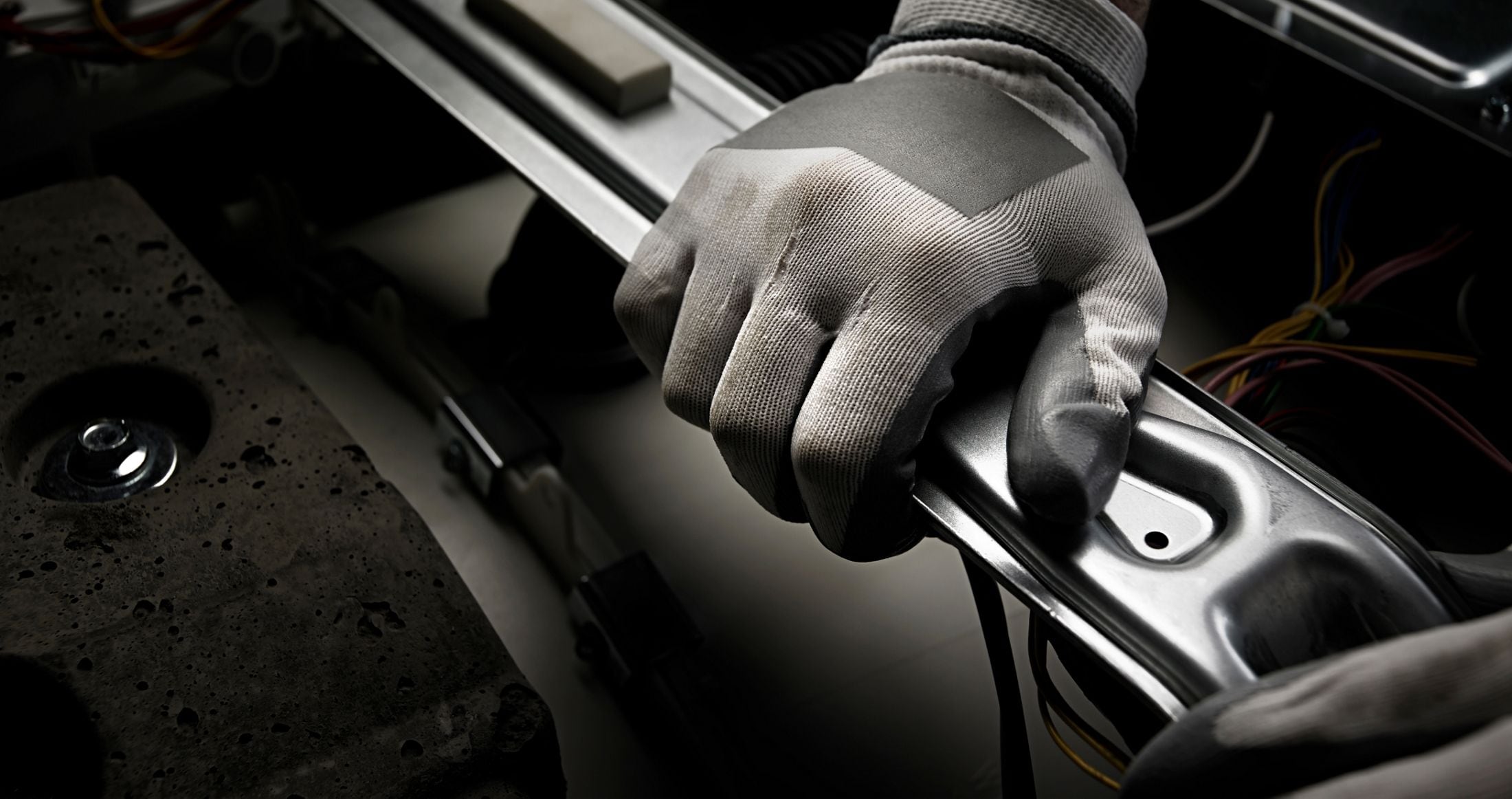 Hand with work glove assembling a laundry machine.