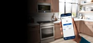 Smartphone in the hand of a person in their kitchen.