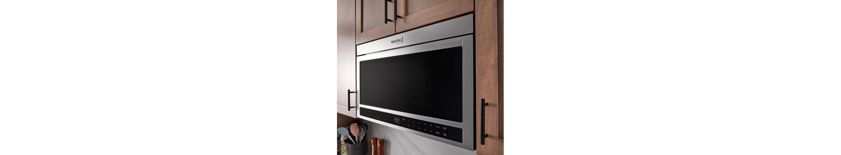 A Maytag® microwave in between kitchen cabinets.