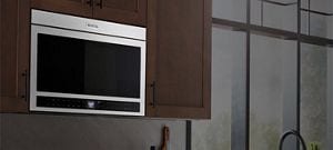 A stainless steel microwave against a dark background.