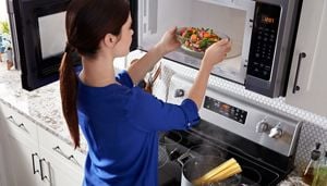 A woman placing a bowl of vegetables in the microwave.